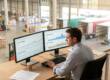 Planificador analizando gráficos de previsión de ventas con un almacén al fondo